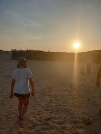 Rear view of woman walking on beach during sunset