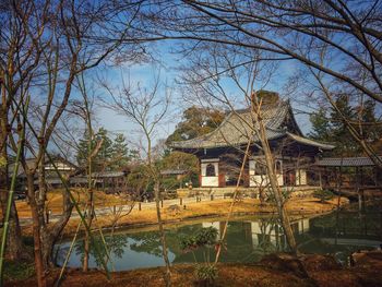 House by lake against sky