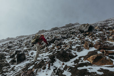 Rear view of person walking on snow covered mountain