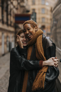 Happy non-binary couple embracing each other while standing at street