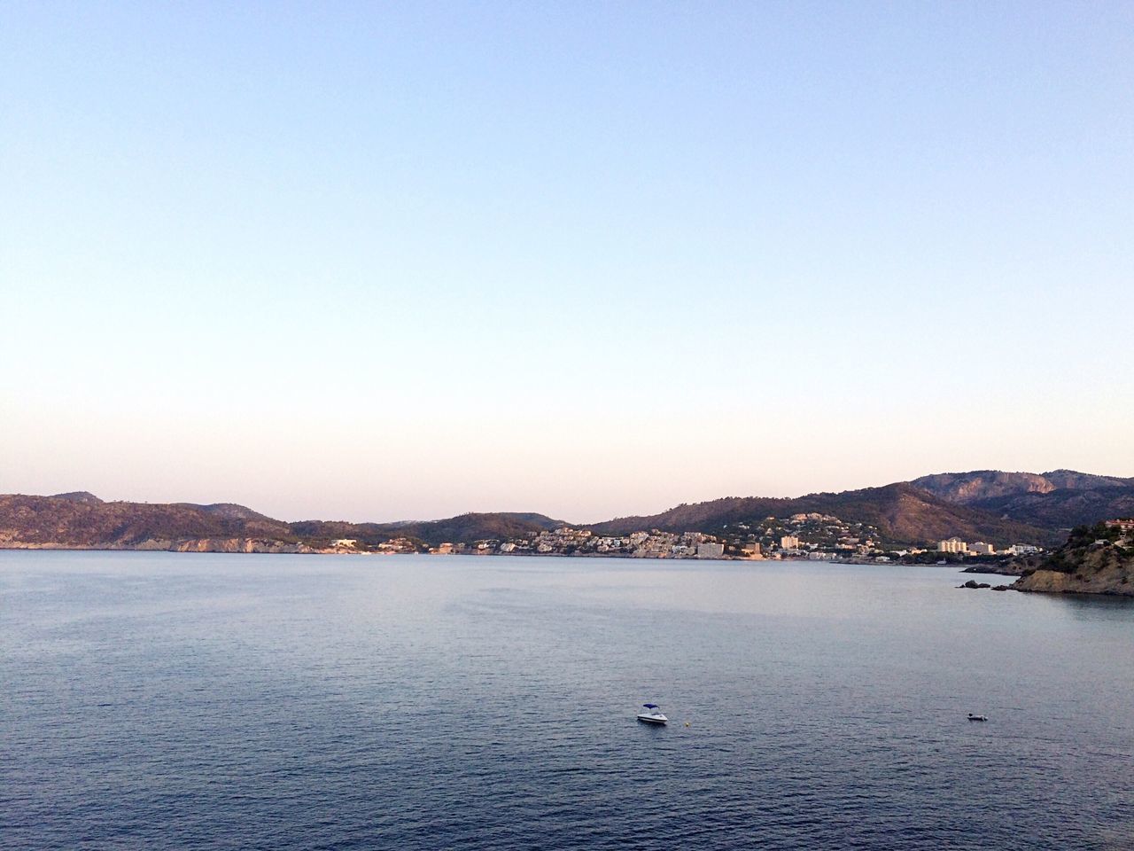 water, clear sky, waterfront, mountain, scenics, tranquil scene, tranquility, beauty in nature, nature, mountain range, blue, rippled, outdoors, idyllic, no people, day, calm, sky, ocean, remote