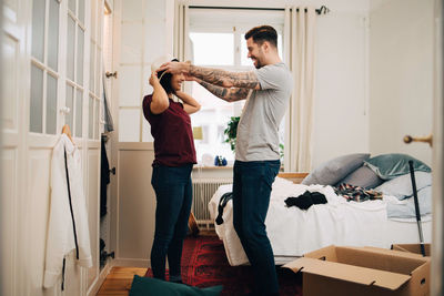 Man adjusting hat on woman at bedroom during relocation