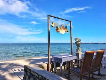 Chairs on table by swimming pool against sky