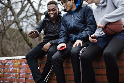 Smiling teenage boy taking selfie with friends after basketball practice in winter