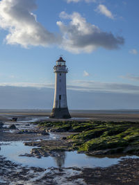 Lighthouse by sea against sky