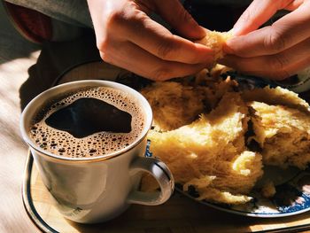 Cropped image of person with black coffee and panettone