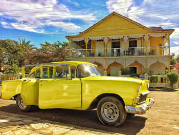 Yellow car on street in city against sky