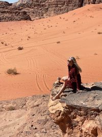 Side view of woman sitting on rock