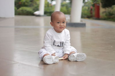 Portrait of a cute boy sitting on the floor in a sporty white costume