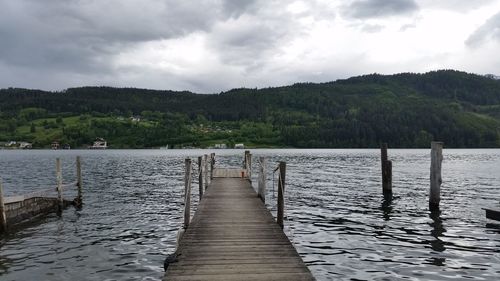 Pier on lake against cloudy sky