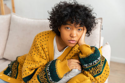 Portrait of young woman sitting on sofa at home