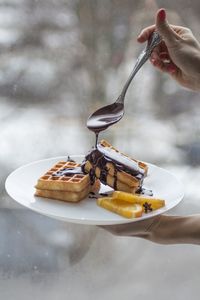 Cropped hand of person pouring chocolate on food