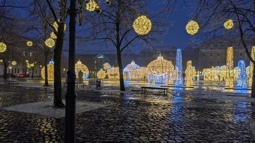 Illuminated street by building at night
