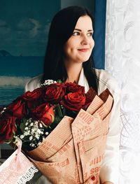 Smiling beautiful woman holding red rose bouquet