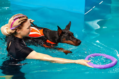 Portrait of young woman with dog in swimming pool