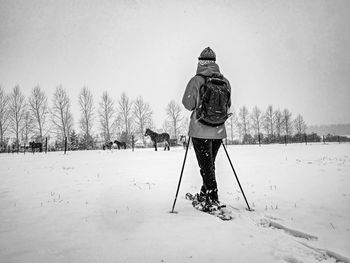 Nice woman on a winter adventure trip on snowshoes. fresh powder snow is falling from dark sky. bw