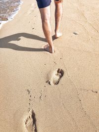 Low section of man walking on shore at beach