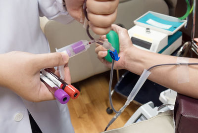 Doctor collecting samples while man donating blood in hospital