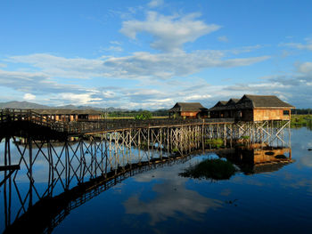 Arch bridge over river by buildings against sky