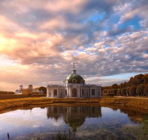 Reflection of building on lake against sky during sunset