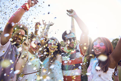 Confetti over happy multi ethnic friends dancing at carnival