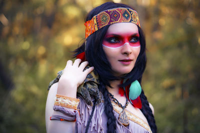 Young woman in traditional clothing carrying tortoise in forest