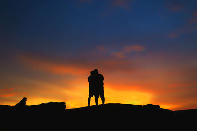 Silhouette of two people against sky during sunset