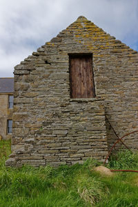 Old abandoned house on field against sky