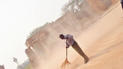 Tilt shot of worker sweeping ground