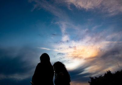 Silhouette couple standing against sky during sunset