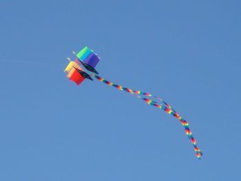 Low angle view of kites against clear blue sky