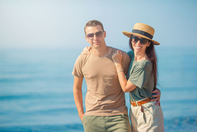 Portrait of smiling friends standing against sea