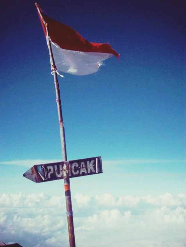 text, low angle view, communication, western script, sky, flag, blue, pole, guidance, road sign, sign, nature, no people, outdoors, red, clear sky, information sign, day, cloud, patriotism