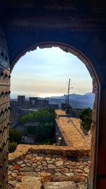 View of buildings against sky seen through arch