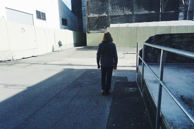 Rear view full length of woman walking by railing on street