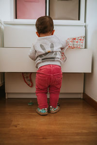 Rear view of girl standing on floor at home