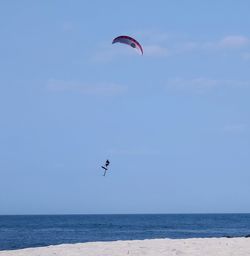 Kite flying over sea against sky