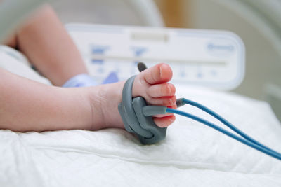 Low section of baby with medical equipment on bed