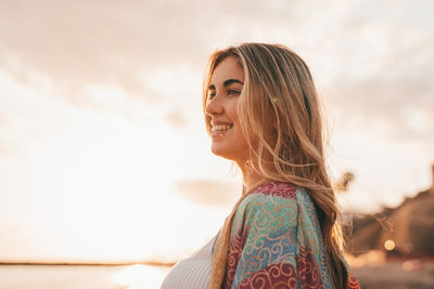 Side view of young woman standing against sky