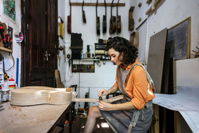 Woman luthier making guitars in her musical instrument workshop