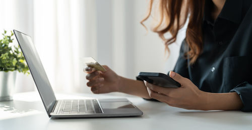 Midsection of woman using laptop on table