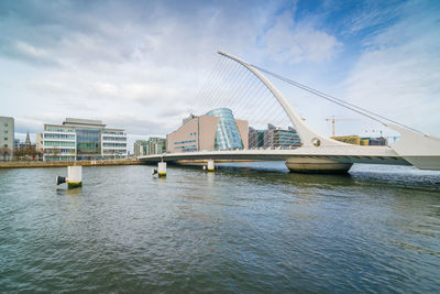 Bridge over river against sky in city