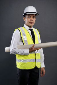 Young man wearing hat standing against gray background