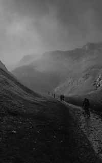 Rear view of man walking on mountain against sky