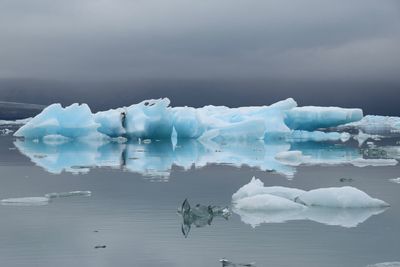 Scenic view of glaciers on lagoon against cloudy sky