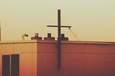 Bird perching on built structure against clear sky