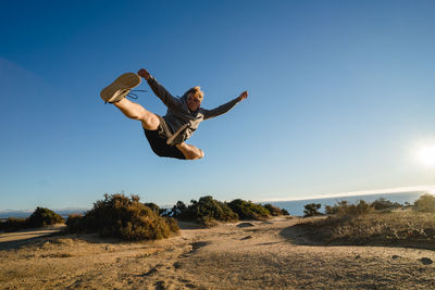Young man jumping against clear sky