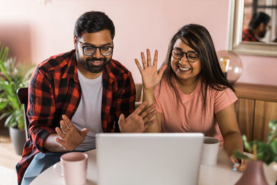 Young woman using laptop while sitting on table