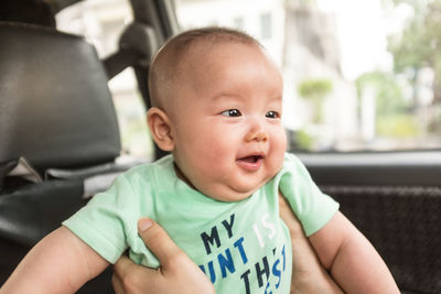Cropped close-up of a parent holding baby in the car