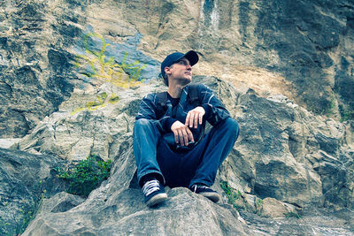 Young man sitting on rock